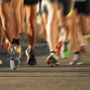 Close-up of runners’ legs in motion during a road race, highlighting athletic endurance and performance.